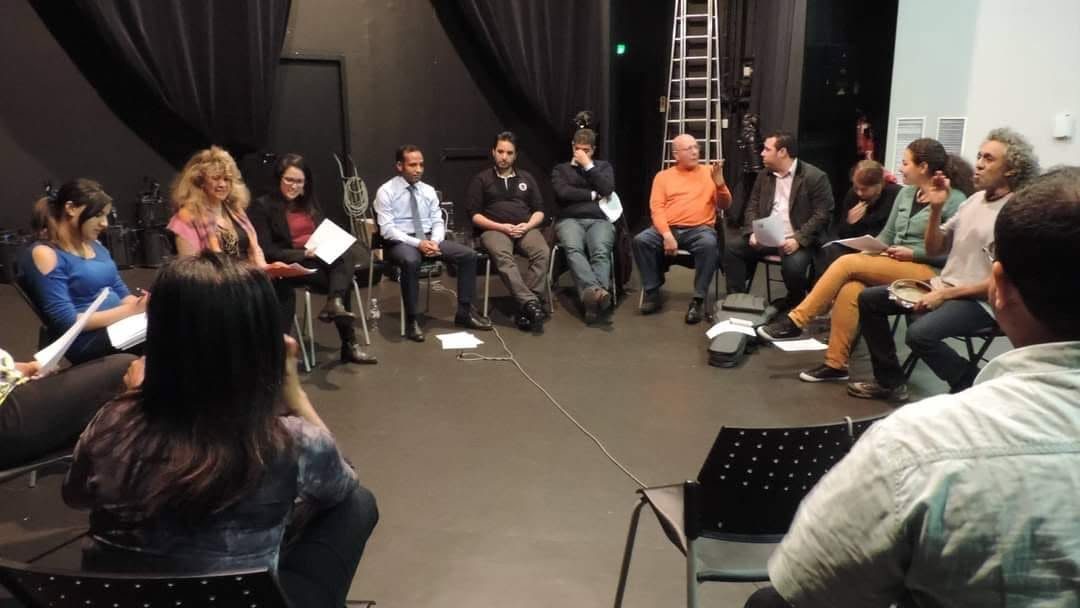 Adultes en cercle, partitions en main, pendant une répétition