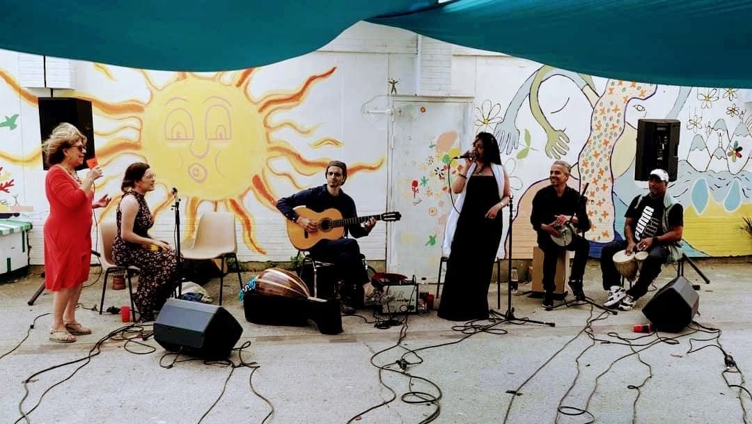 Six musiciens jouent devant une fresque murale en plein air