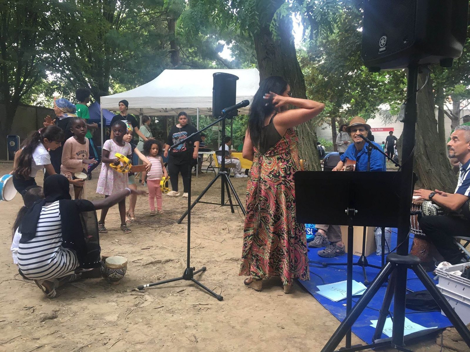 Des enfants jouent du tambourin avec les musiciens dans un parc
