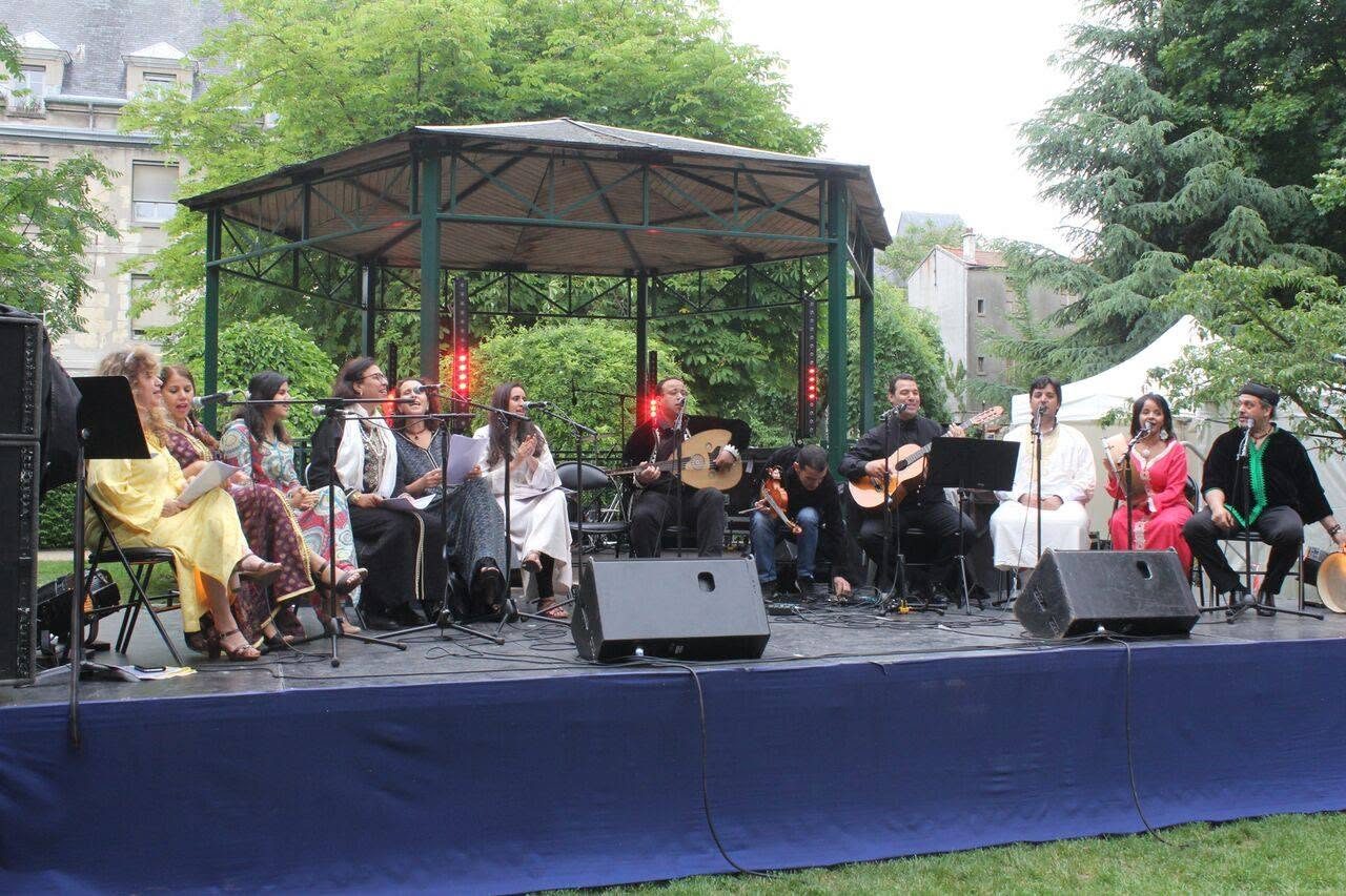 Grand plateau : la chorale de femmes en caftans et l'orchestre de Guedra sous une tonnelle