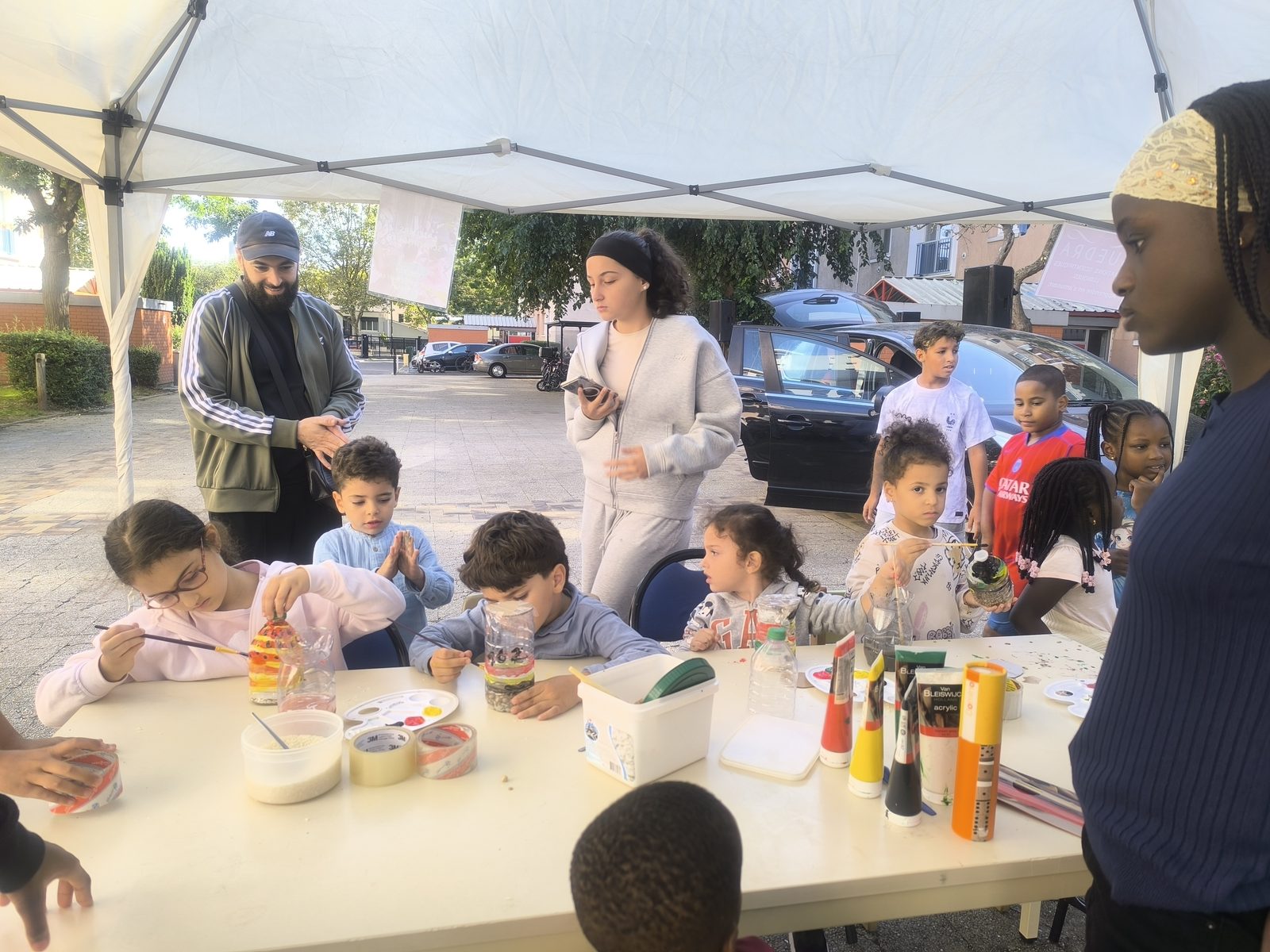 Enfants peignent sous une tente au pied d'une résidence
